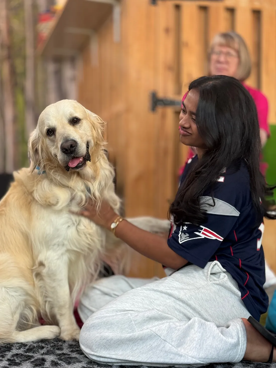 A student strokes a happy golden retriever during a Moment to Paws event